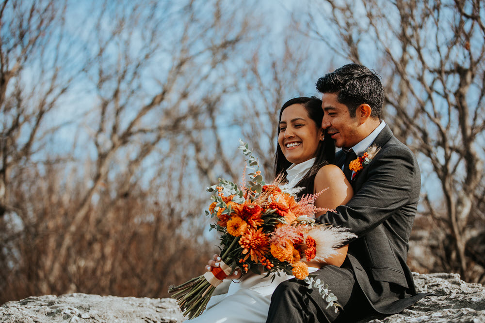 Bridal couple holding a bouquet featuring vibrant fall colors.