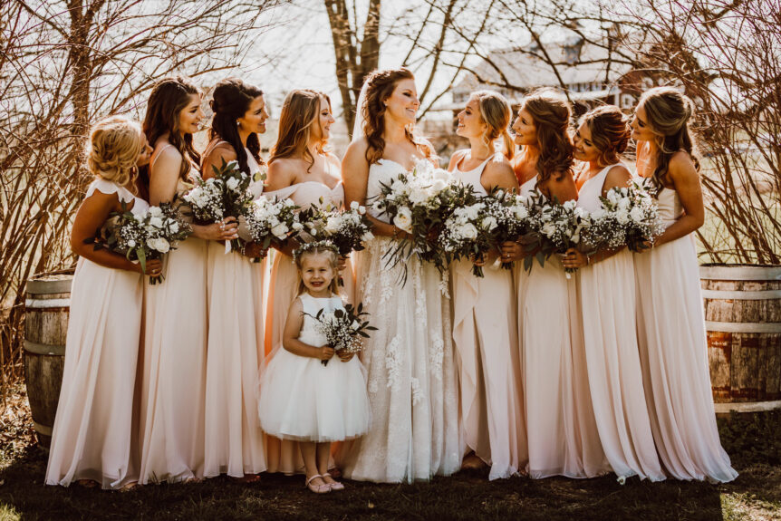 Bride and bridesmaids sharing a happy moment on the lawns at Zion Springs, an elegant rustic barn wedding venue in Loudoun.