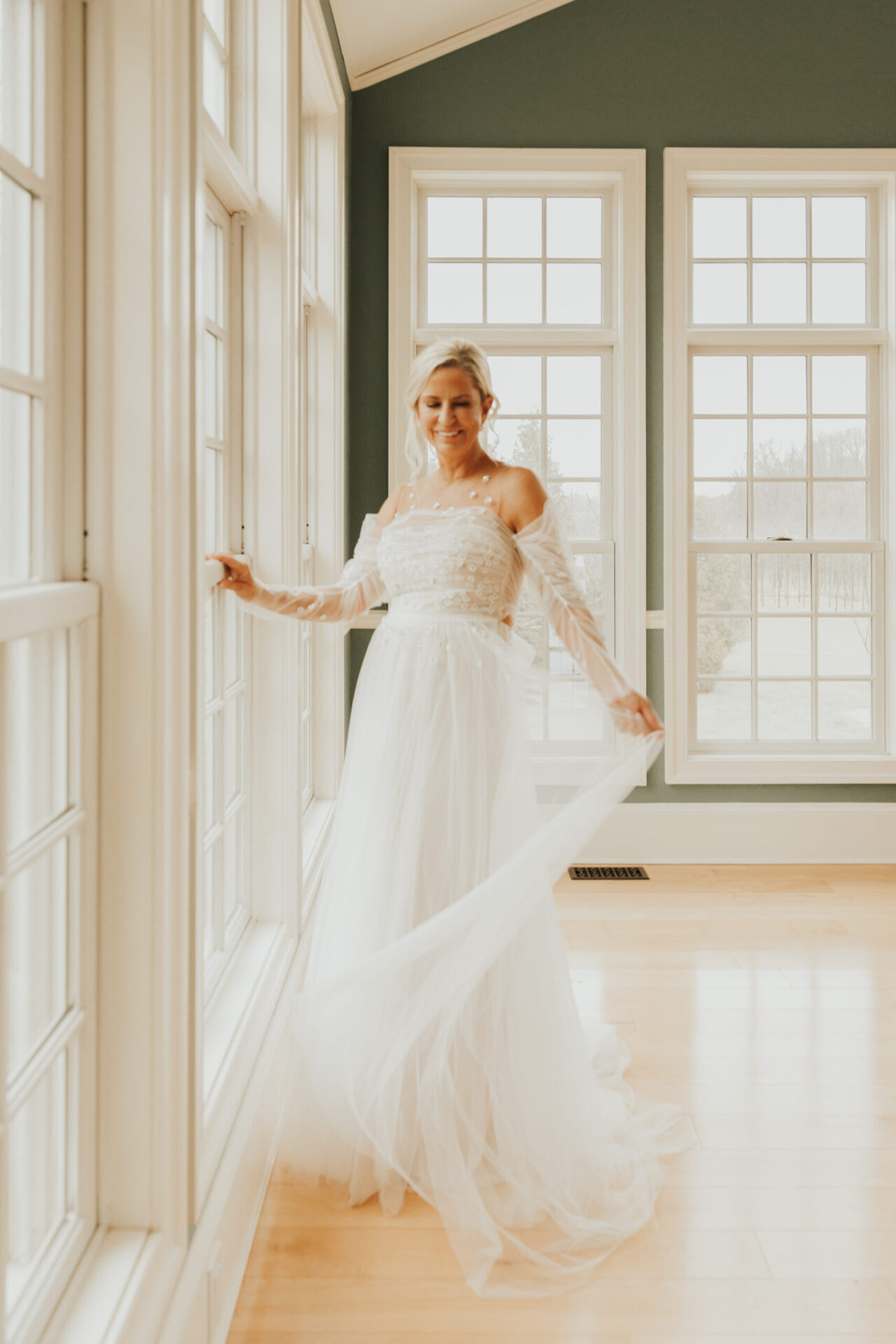 Zion Springs Real Wedding bride in an ethereal wedding gown standing in the soft light of the Manor House music room