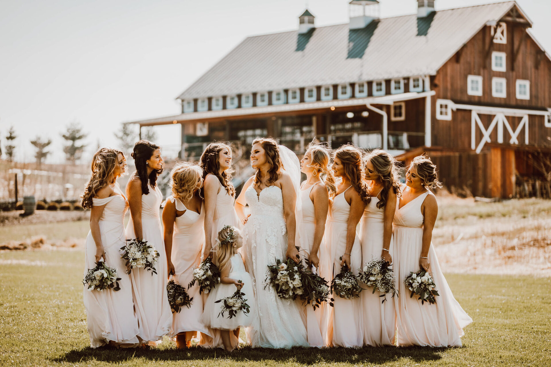 Brides and bridesmaids sharing a fun moment by the barn at Zion Springs, a rustic elegant wedding venue in Virginia.